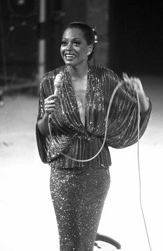 a woman in a sequined dress holding a microphone and singing into a mic