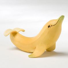 a banana shaped like a dolphin with its mouth open and eyes closed, sitting on a white surface