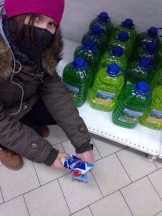 a person kneeling down next to a shelf filled with bottled water