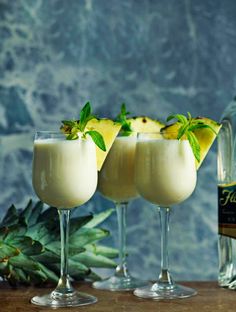 three glasses filled with white liquid and topped with pineapple