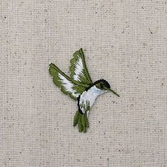 a white and black bird with green wings on a beige cloth textured wallpaper