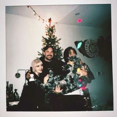 a group of people standing in front of a christmas tree