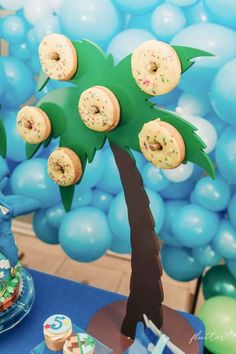 a palm tree with doughnuts on it in front of blue balloons and other decorations