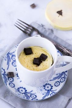 a cup filled with pudding sitting on top of a blue and white plate next to a fork