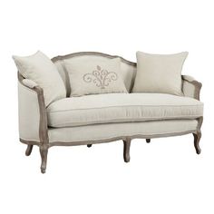 a white couch with two pillows on it's back and an ornate armrest