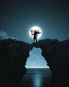 a person standing on top of a cliff under a full moon