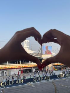 two hands making a heart with their fingers in front of a crowd at an air port