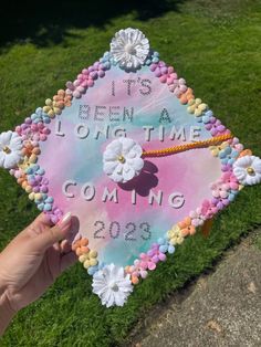 someone holding up a decorated graduation cap that says it's been a long time coming