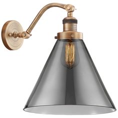 an industrial style wall light with a metal cone shade on the side and gold accents