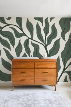 a dresser in front of a wall with leaves painted on the walls and flooring