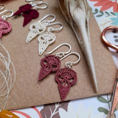 several pairs of crocheted earrings sitting on top of a table next to scissors