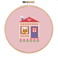 a cross stitch pattern with a house and cat