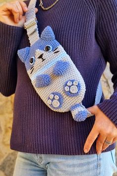 a woman is holding a crocheted cat purse