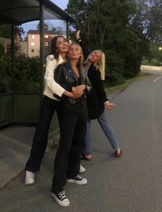 three women are standing in front of a bus and one is holding her head up