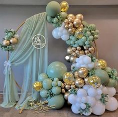 a balloon arch is decorated with gold, white and mint green balloons in the shape of a tree