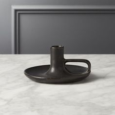 a marble counter top with a black vase on the edge and a gray door in the background