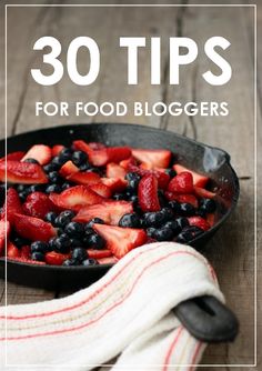 a skillet filled with berries and blueberries sitting on top of a wooden table