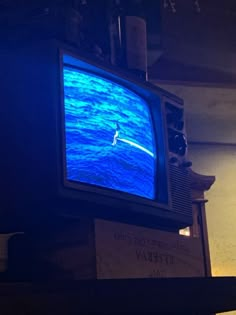 an old television with a blue screen on it's display stand in a dark room