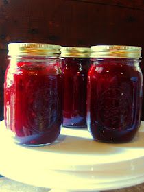 three jars filled with red liquid sitting on top of a white plate