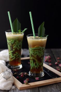 two glasses filled with drinks sitting on top of a tray