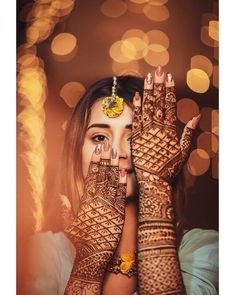 a woman with henna on her hands and face covered in yellow flower decorations, looking at the camera