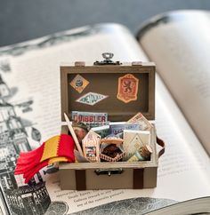 an open book on top of a table next to a box with items in it