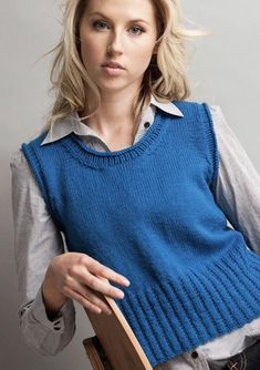 a woman in a blue sweater holding a wooden chair