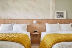 two beds in a hotel room with white and yellow comforters on the headboards