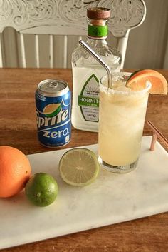 an alcoholic drink on a tray with limes and oranges