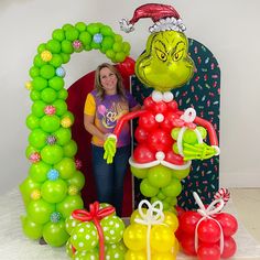 a woman standing in front of a balloon arch with balloons surrounding it and an image of the grin