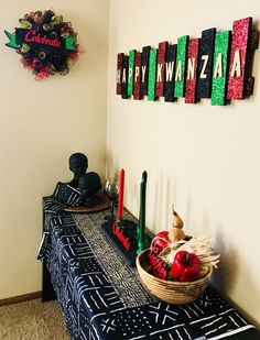 a black and white table topped with an apple basket next to a wall hanging sign