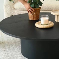 a table with a candle and potted plant on it in front of a couch