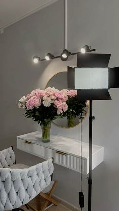 a flower arrangement in a vase on top of a white table next to a chair