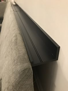 a close up view of a black shelf on the side of a couch in a living room