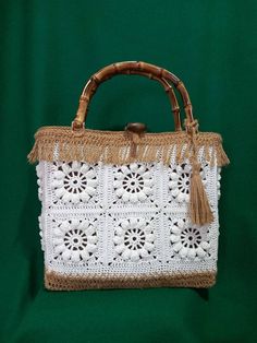 a white crocheted bag with tassels and fringe on it's handle