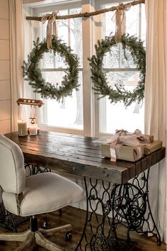 an old sewing table with christmas wreaths on the window sill and two chairs