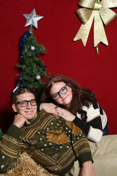 a man and woman laying next to each other in front of a decorated christmas tree