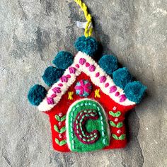 a felt house ornament hanging on a rock