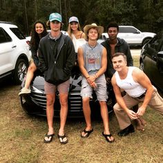 a group of people standing next to each other in front of a car