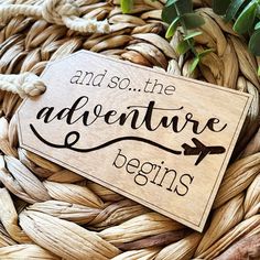 a wooden sign that says and so the adventure begins on top of some woven material