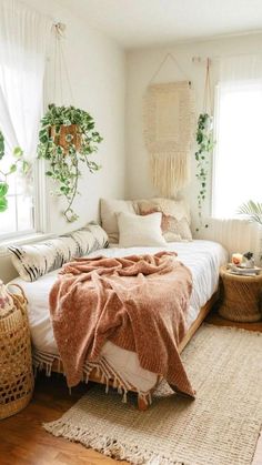 a bedroom with white walls, wooden floors and lots of greenery on the windowsill