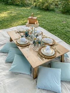 a wooden table topped with blue pillows and plates