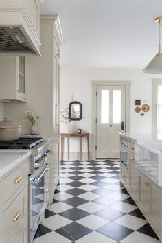 a kitchen with black and white checkered flooring next to a stove top oven