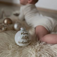 a baby laying on the floor next to a christmas ornament