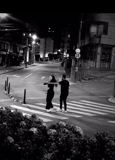 two people crossing the street at night time