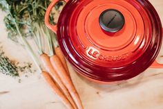 some carrots are laying next to a red pot