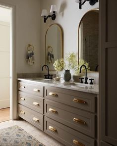 a bathroom with two sinks and mirrors on the wall next to a door that leads to another room