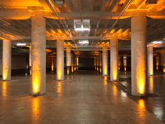 an empty parking garage with yellow lights on the ceiling and columns in the floor,