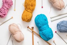 yarn and knitting needles laid out next to each other on a white surface with crochet hooks