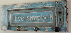 a sign that says live simply hanging on a wall with knobs attached to it